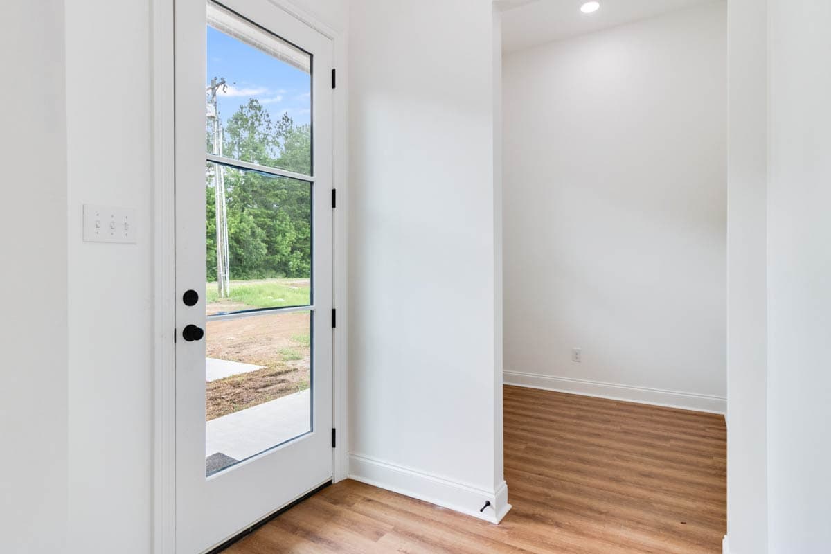 Interior view of an entryway with a glass door, light wood flooring, and a view of the exterior.