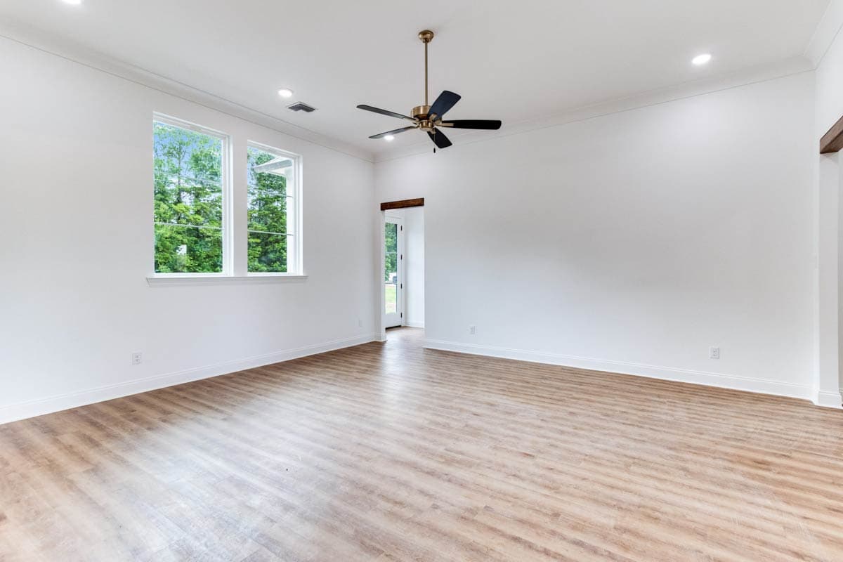 Interior view of a spacious room with wood-look flooring, white walls, recessed lighting, a ceiling fan, and a double window.