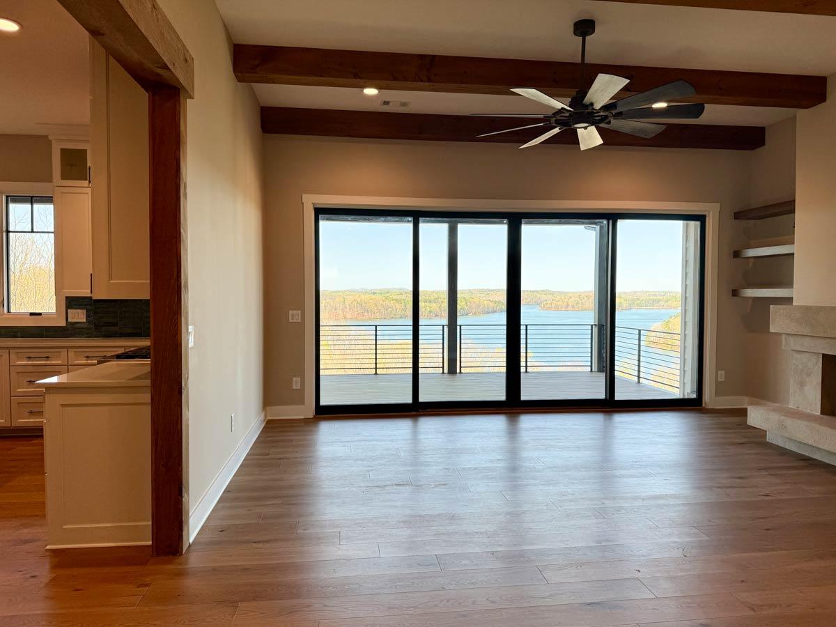 Interior view of living area with hardwood floors, exposed wood beams, large sliding glass doors, and a modern fireplace.