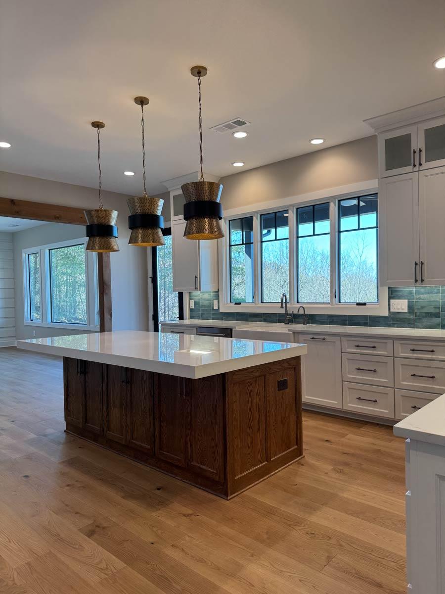 Kitchen interior featuring a large island with white quartz countertop, shaker cabinets, tiled backsplash, and pendant lighting.