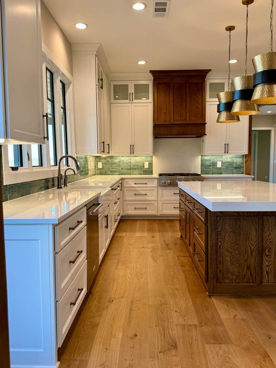 Kitchen with white Shaker cabinets, wood island, quartz countertops, subway tile backsplash, and wood flooring.