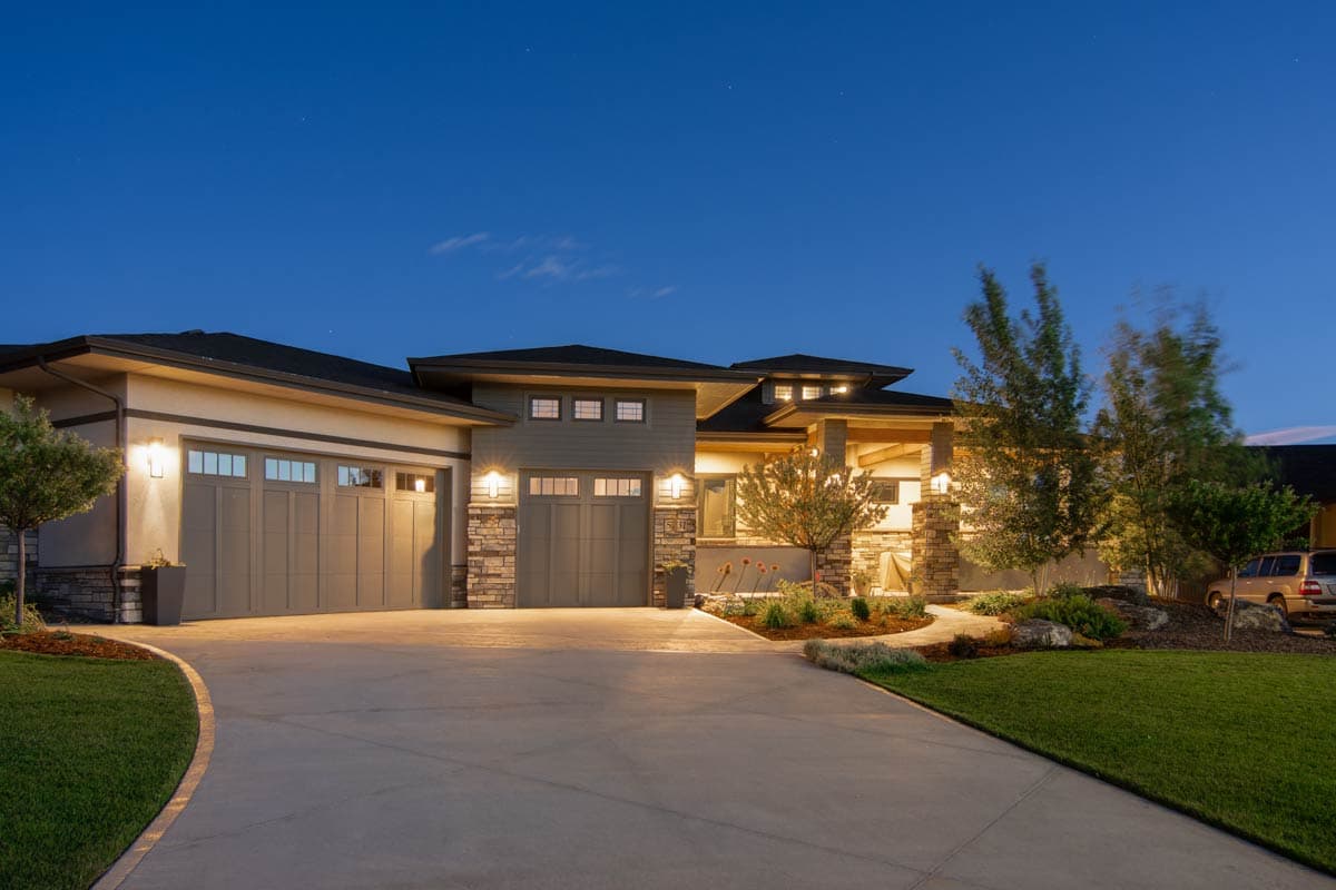 Modern house plan exterior with a three-car garage, stone accents, multiple rooflines, and a covered entryway.