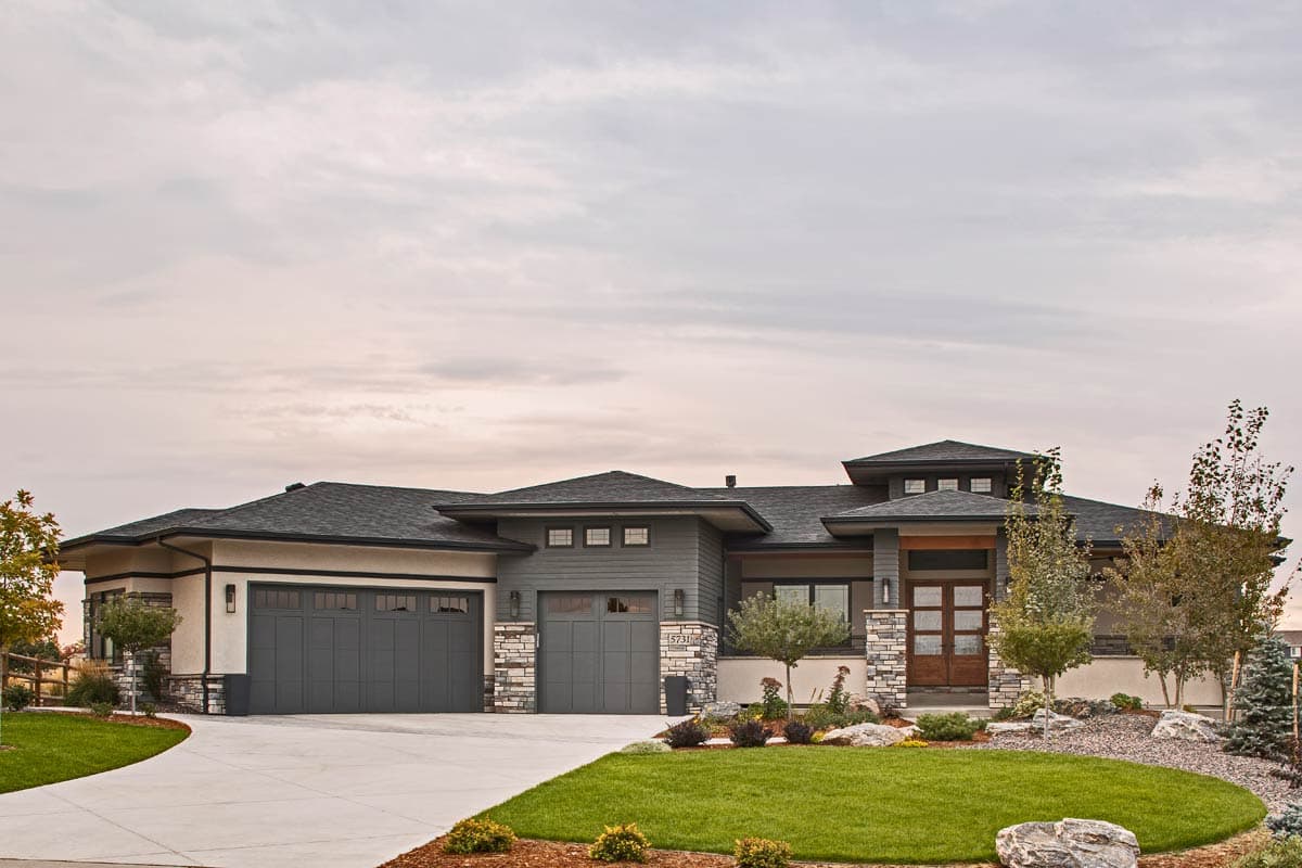 Modern house plan exterior with a low-pitched roof, multiple gables, three-car garage, and stone accents.