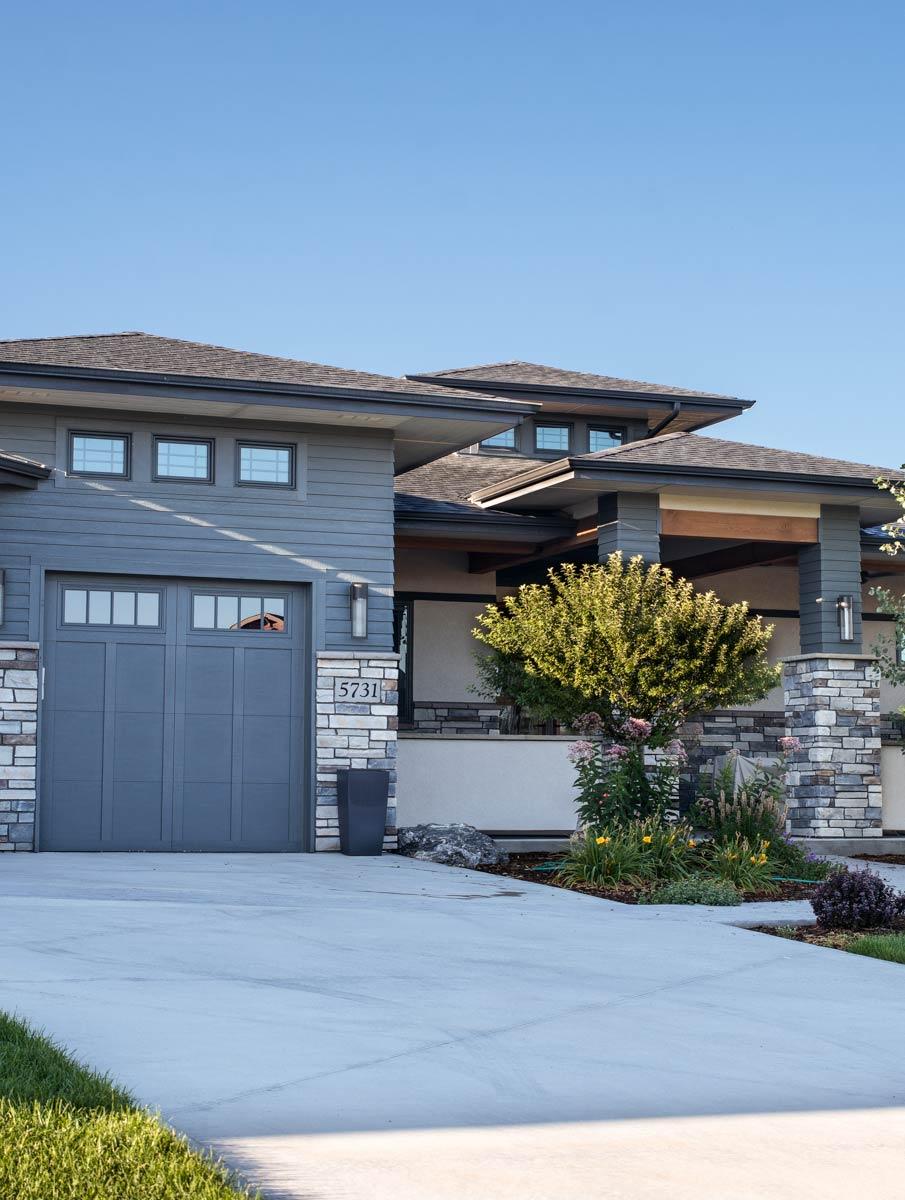 Modern house plan exterior with layered rooflines, stone accents, wide siding, and a covered entry.
