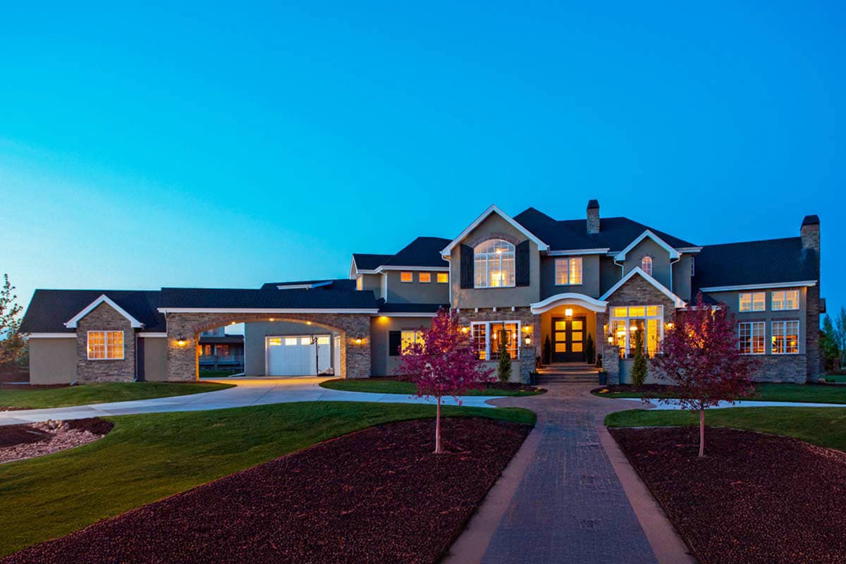 House plan exterior. Two-story home with arched entry to garage, multiple gables, and a brick and stone facade. Symmetrical front entry.