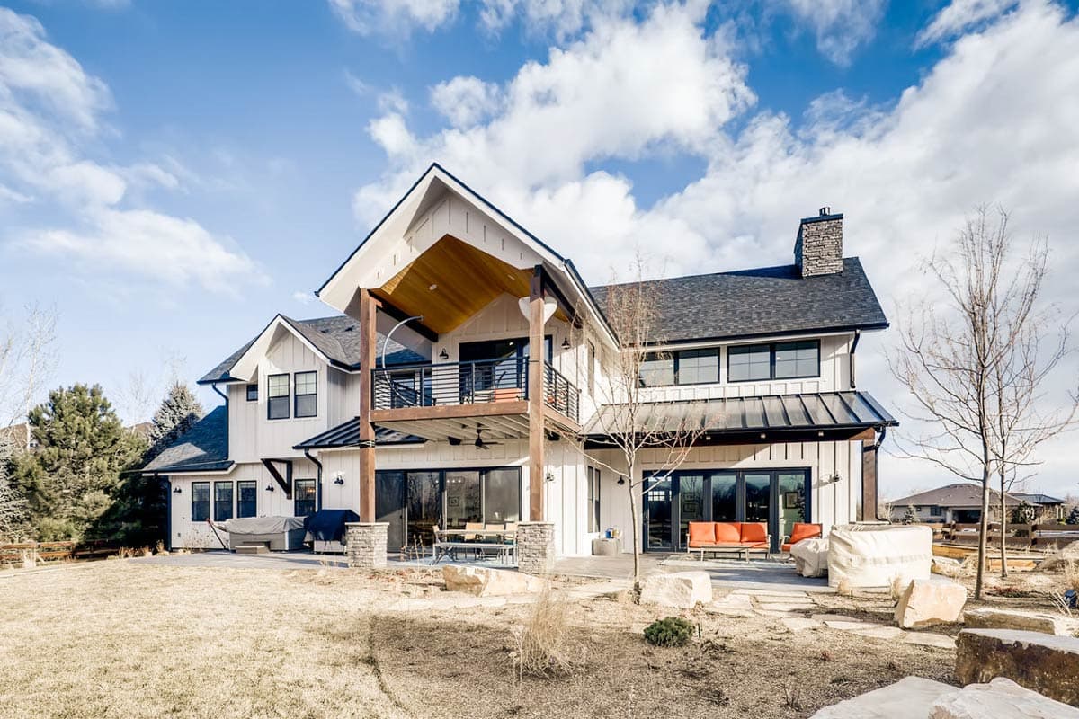 Modern Farmhouse house plan exterior with two stories, a prominent gable, covered balcony, and stone chimney.
