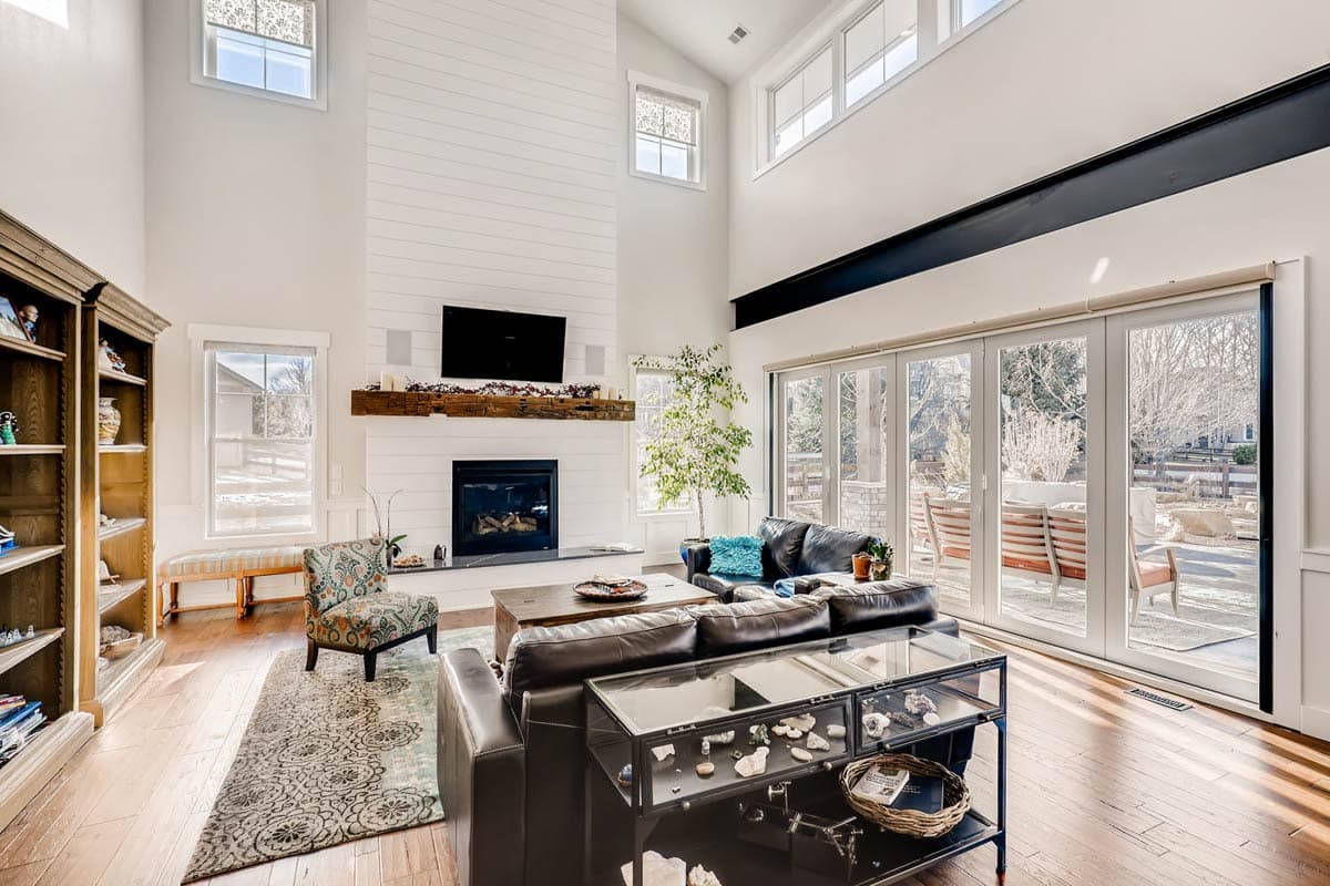 Great room with shiplap fireplace, vaulted ceiling, exposed beam, and folding glass doors leading to patio.