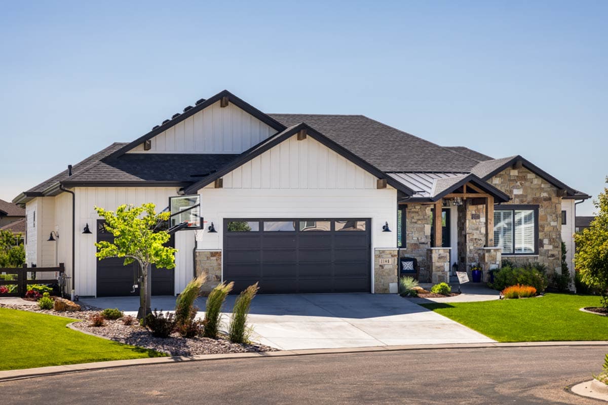 House plan exterior with board and batten siding, multiple gables, and a stone facade entry porch. Garage door is front facing.