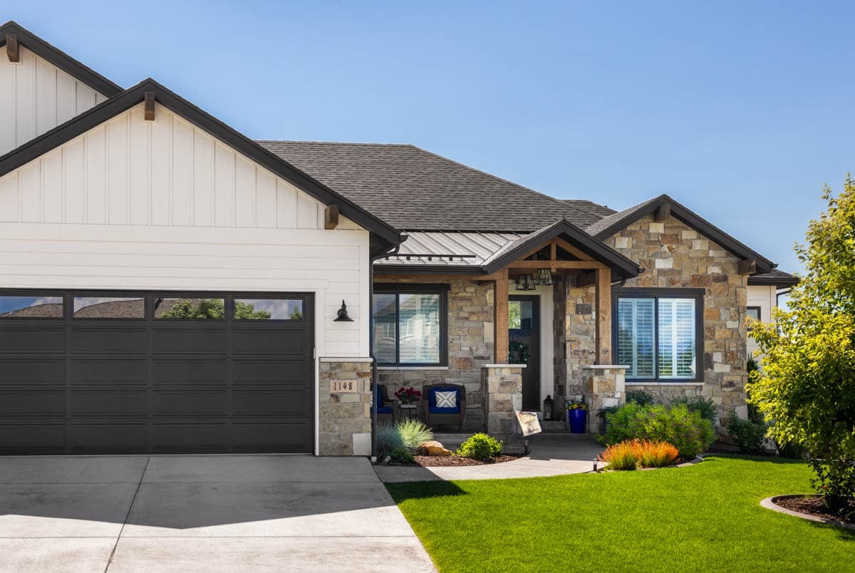House plan exterior showing a Modern Farmhouse style, one-story home with stone and board-and-batten siding, gabled rooflines, and a covered entry.