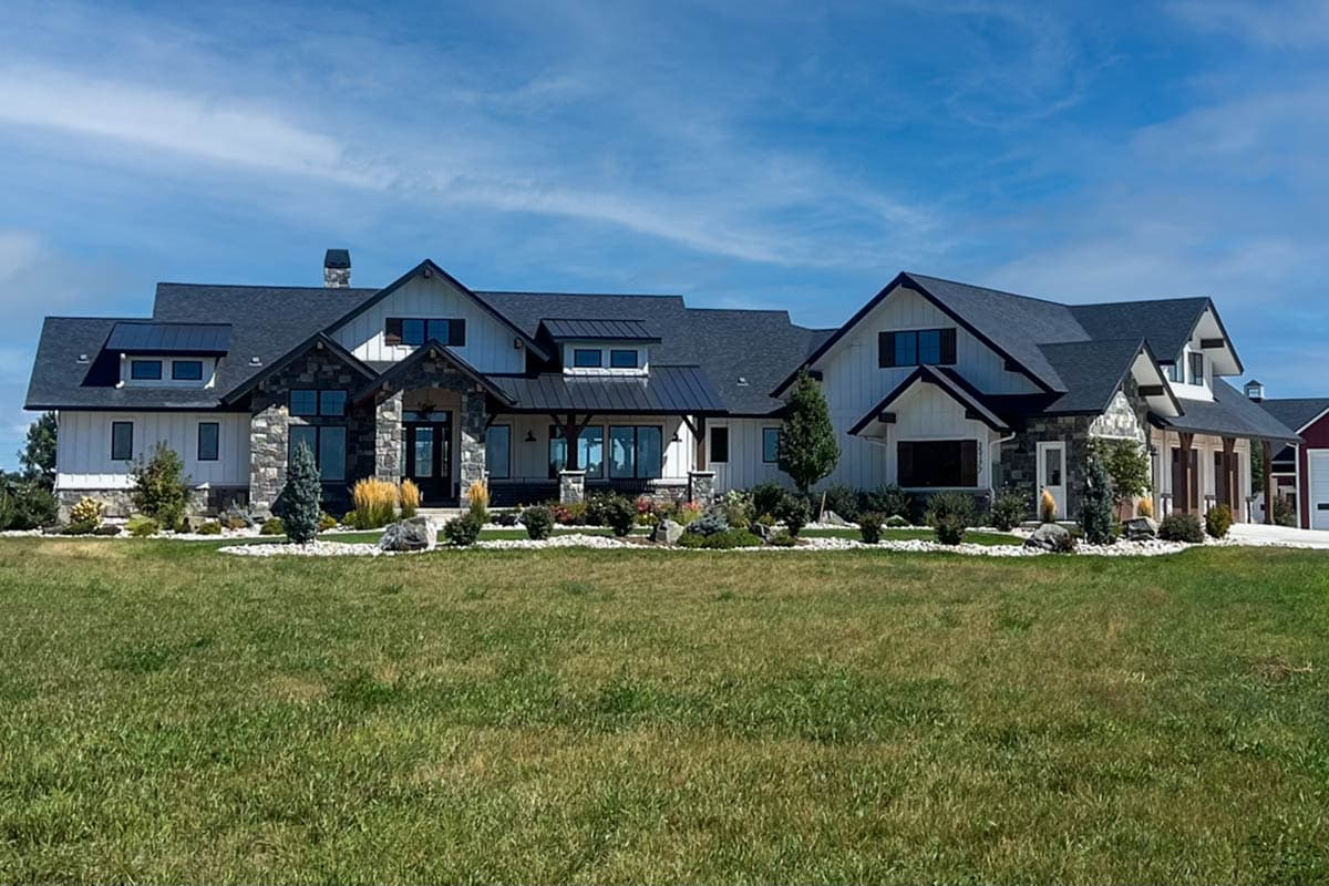 Modern Farmhouse exterior with gabled roof, stone accents, and covered porch. Two-story house plan with garage on the right.