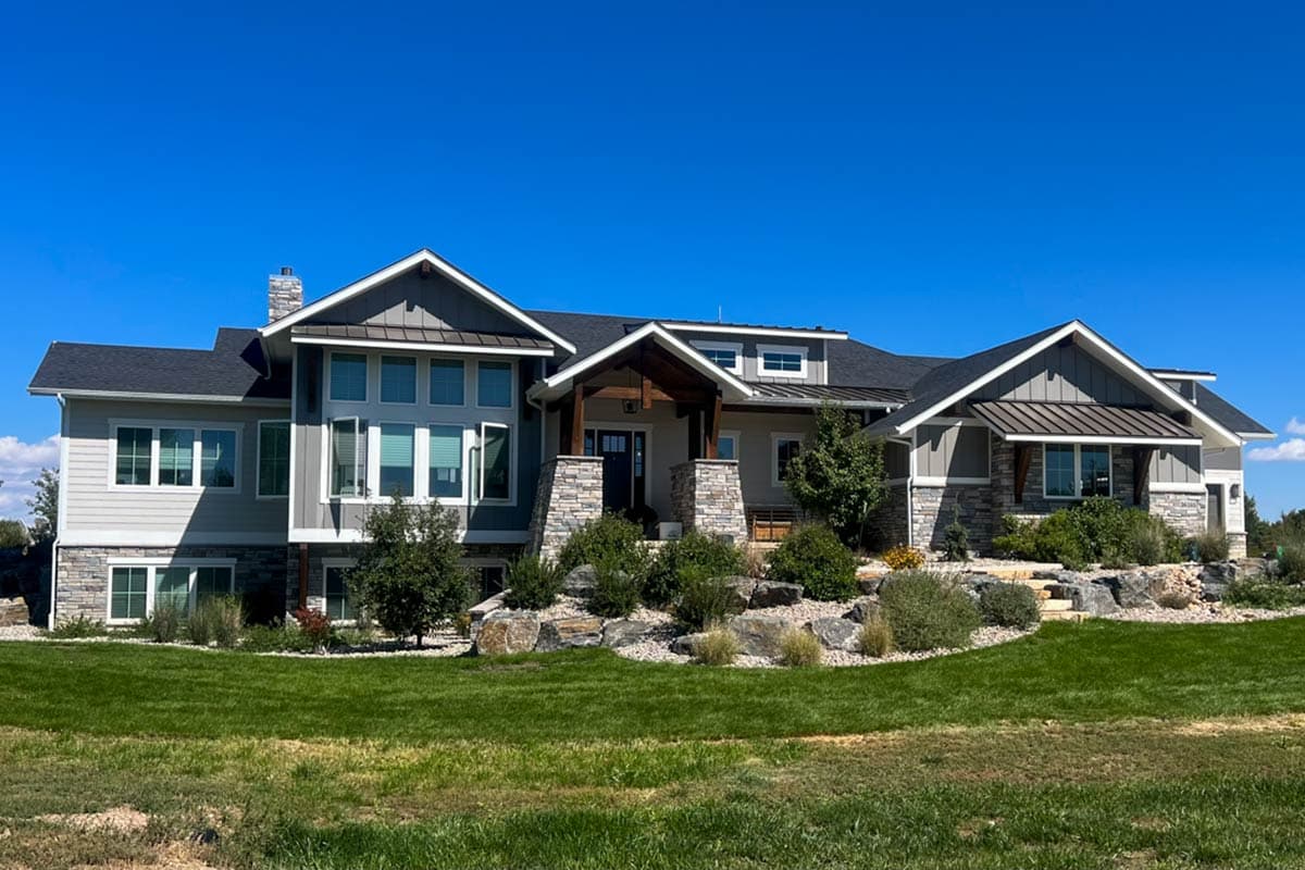 House plan exterior with Craftsman-style elements. Features include multiple gables, a covered porch, and stone accents. Two-story design.