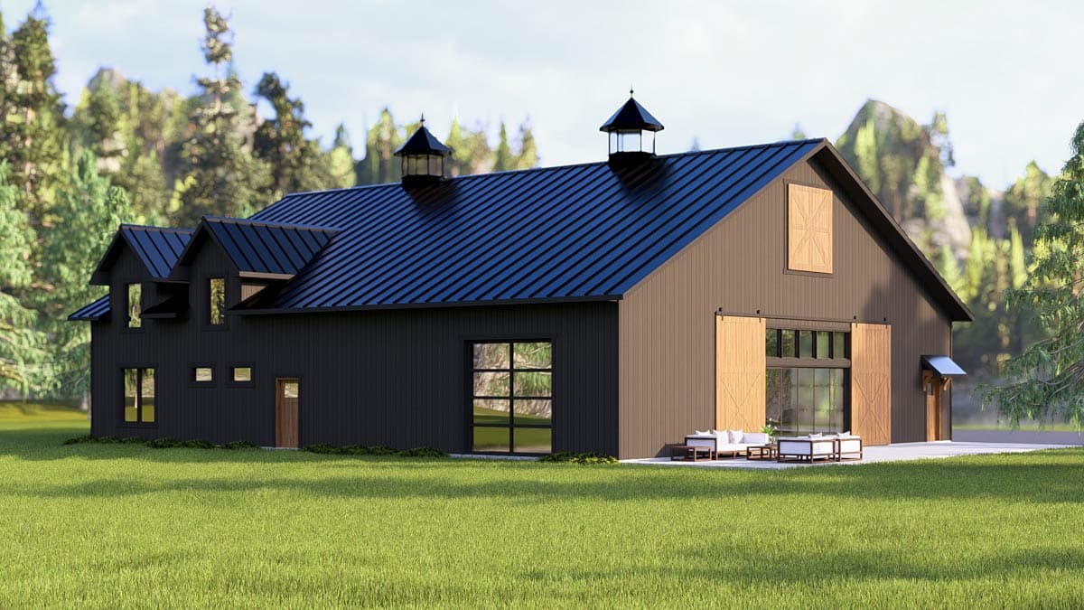 Modern barn-style house with a dark exterior, a black metal roof, and large glass windows. A small patio sits outside.