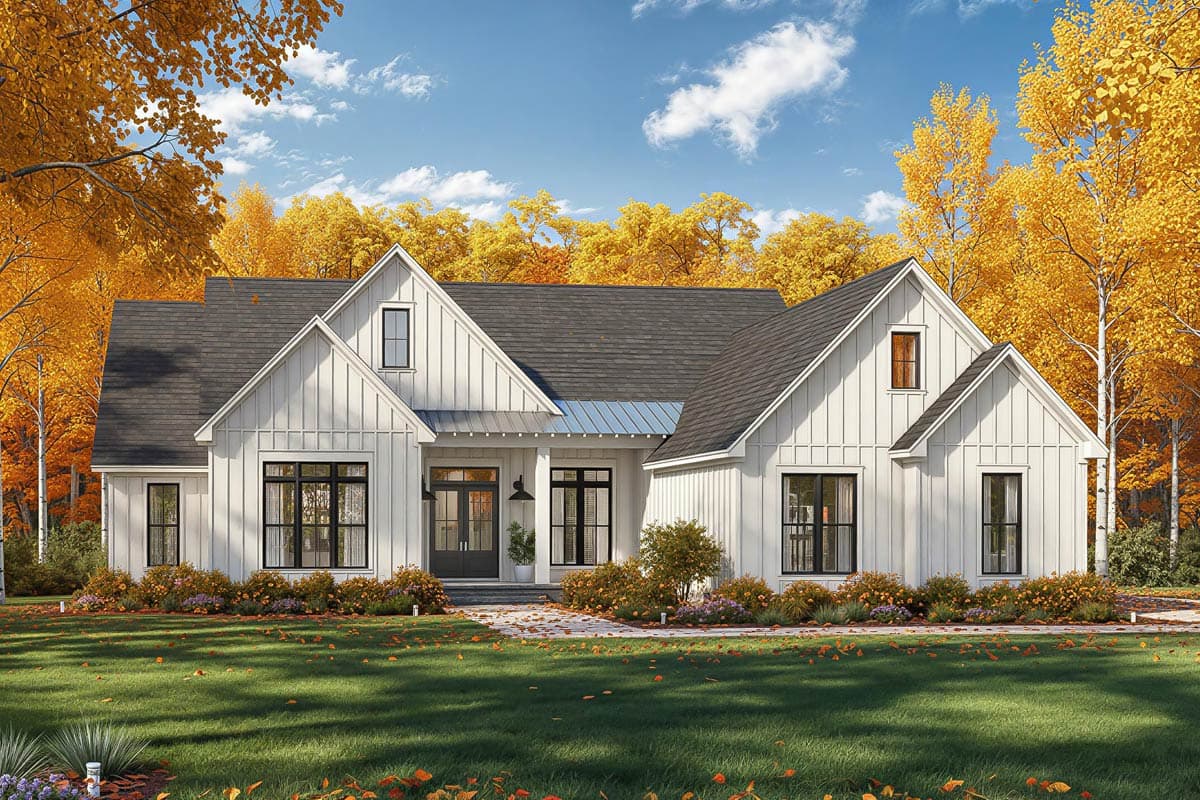 A white farmhouse with black window frames, set against a backdrop of vibrant yellow autumn trees and a blue sky.