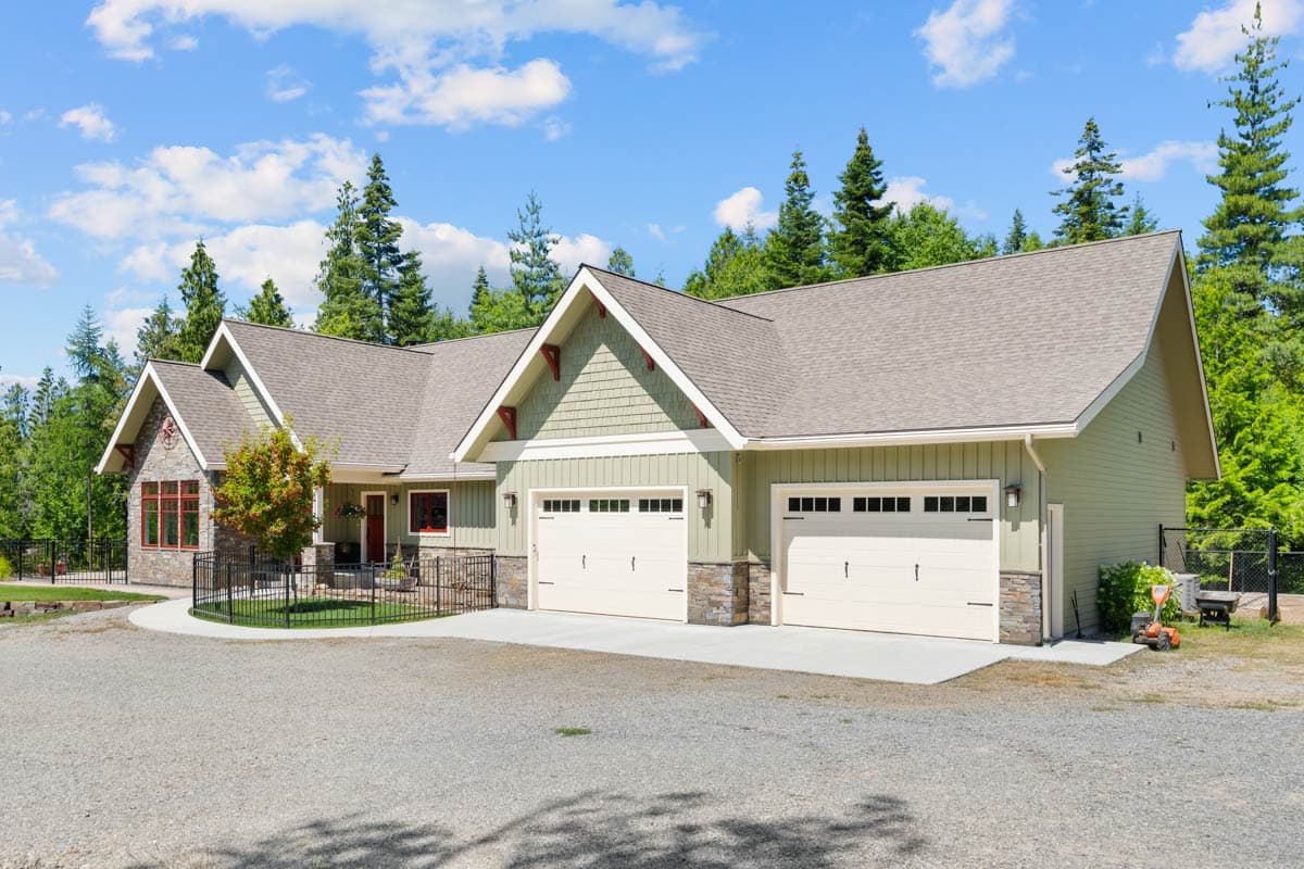 House plan exterior showing a one-story Modern Farmhouse with a three-car garage, gables, and stone accents.