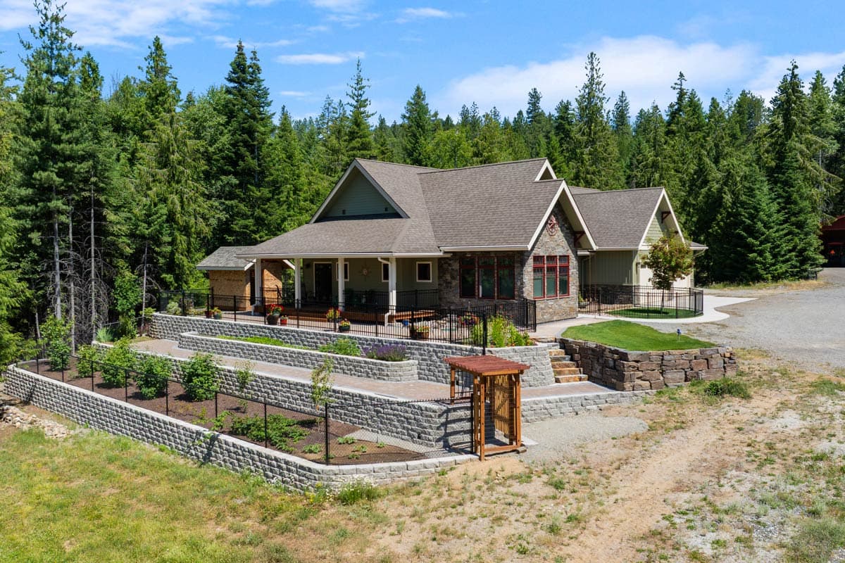 House plan exterior: Craftsman style, 1.5 stories, porch, gables, stone accents, and tiered landscaping.