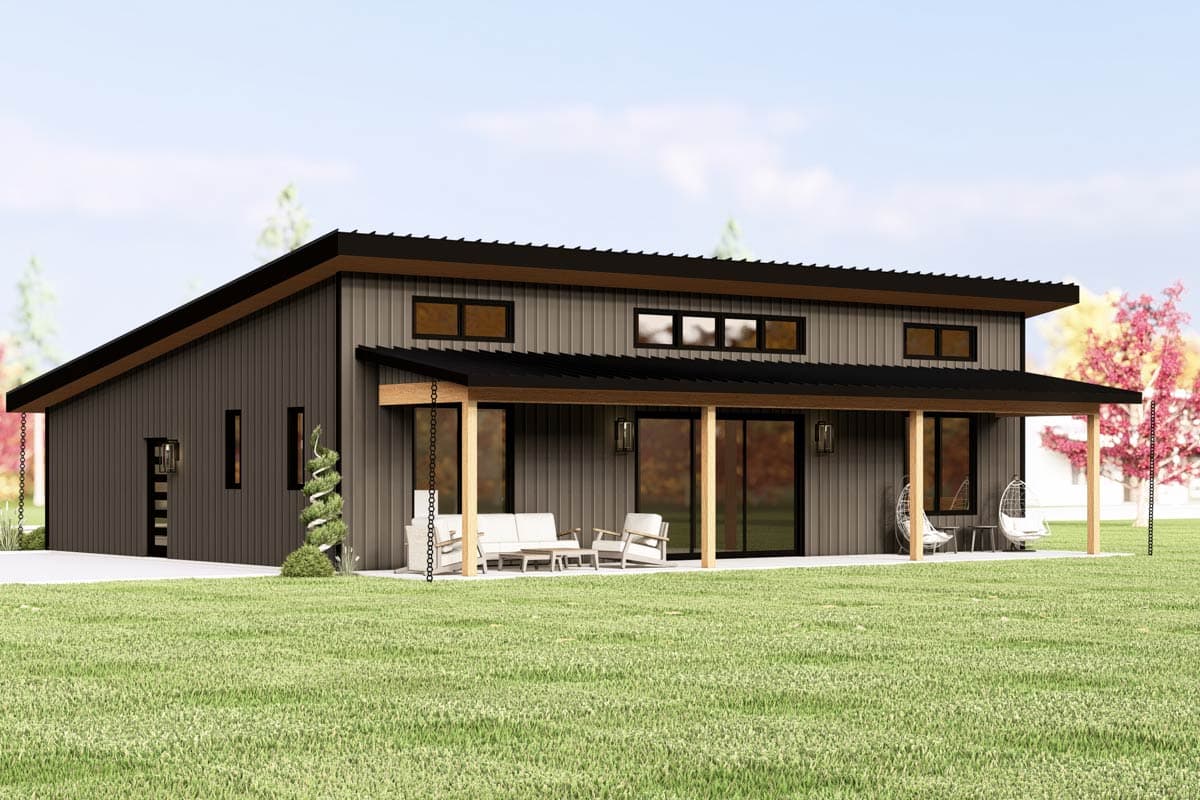 Modern, two-story house with a flat roof. A covered patio with outdoor seating is visible, plus hanging chairs. The house is surrounded by grass.