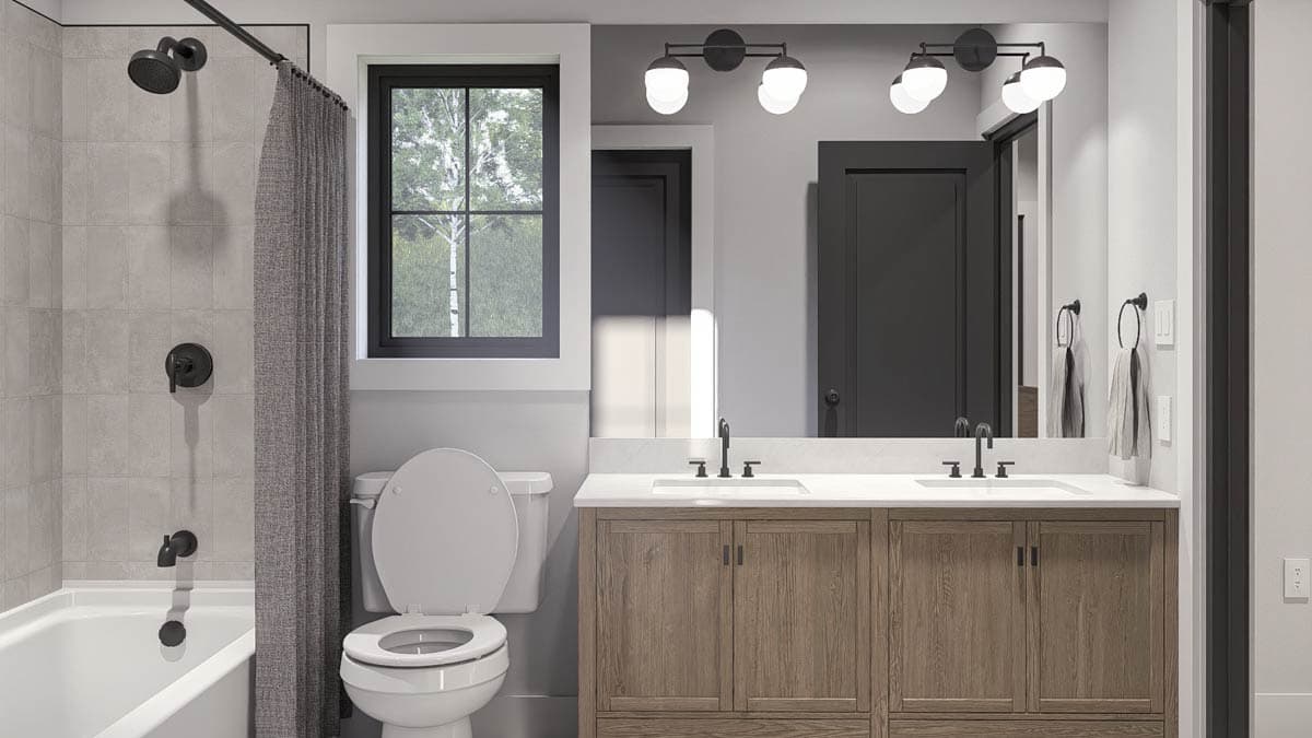 Bathroom interior with tub, toilet, double vanity with wood cabinets, and black fixtures.