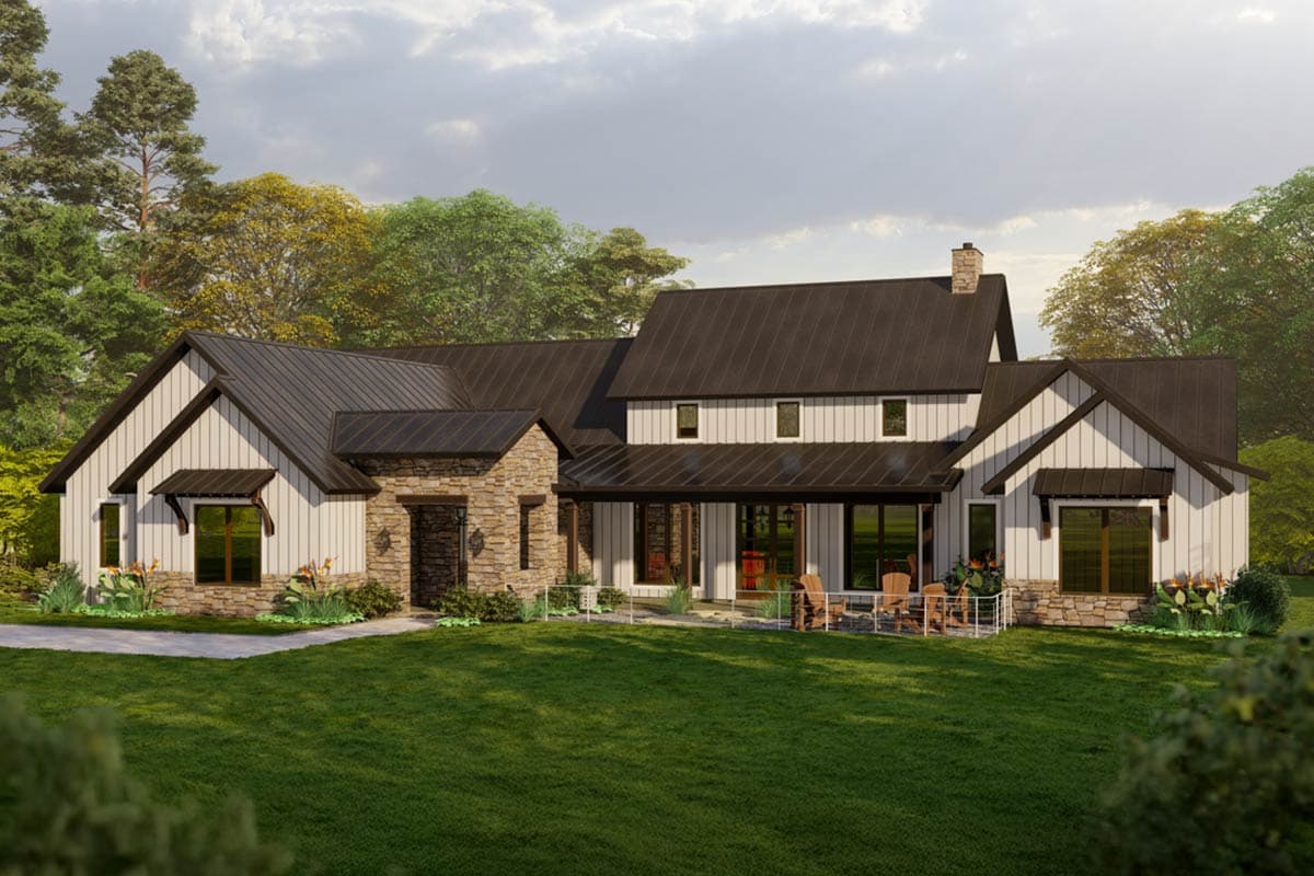 A modern farmhouse with a dark roof and white siding is set on a lush green lawn. Stone accents and large windows are featured.