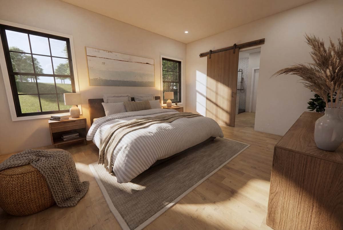 A modern bedroom with a large bed, wooden furniture, and a sliding barn door leading to a bathroom. The room is brightly lit with natural light.