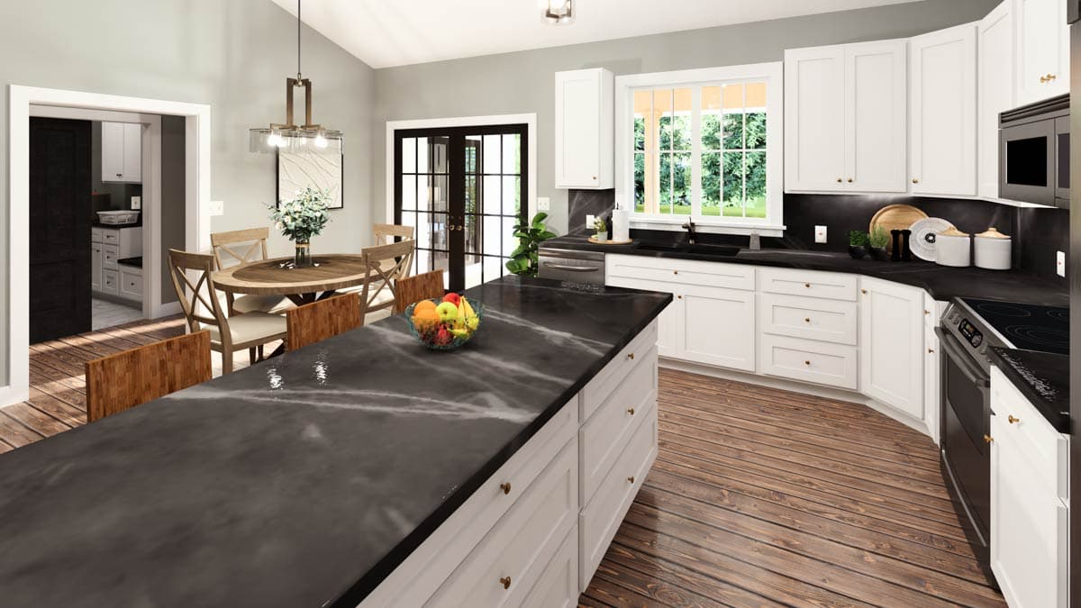 Kitchen and dining area with white cabinets, dark countertops, island, round table, and vaulted ceiling.