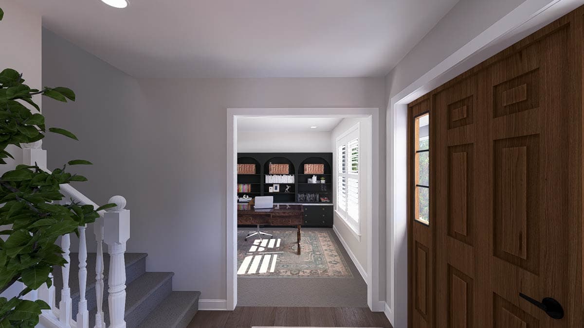 Interior view of house entry, showing a wood door, staircase, and view into a home office with built-in shelving.