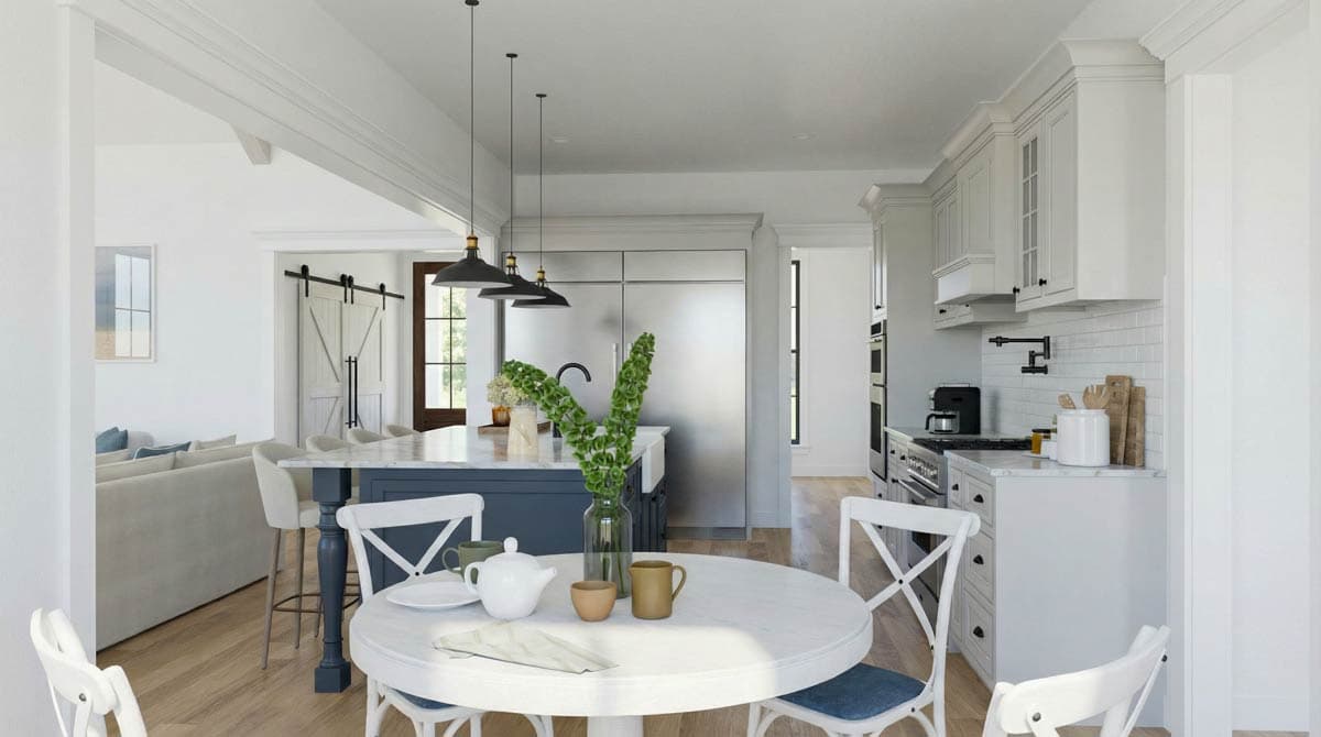 A modern kitchen with a round table and chairs in the foreground. In the background, an island, cabinets, and appliances create a spacious design.