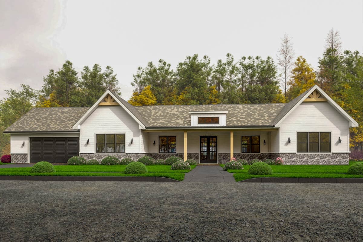 A white farmhouse with a dark garage door and a stone facade. The house has a covered front porch with dark double doors and landscaping.