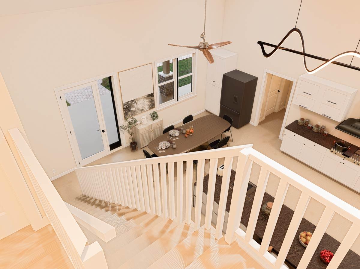 Interior view of dining area and kitchen with vaulted ceiling, ceiling fan, dining table, island, and white cabinets.
