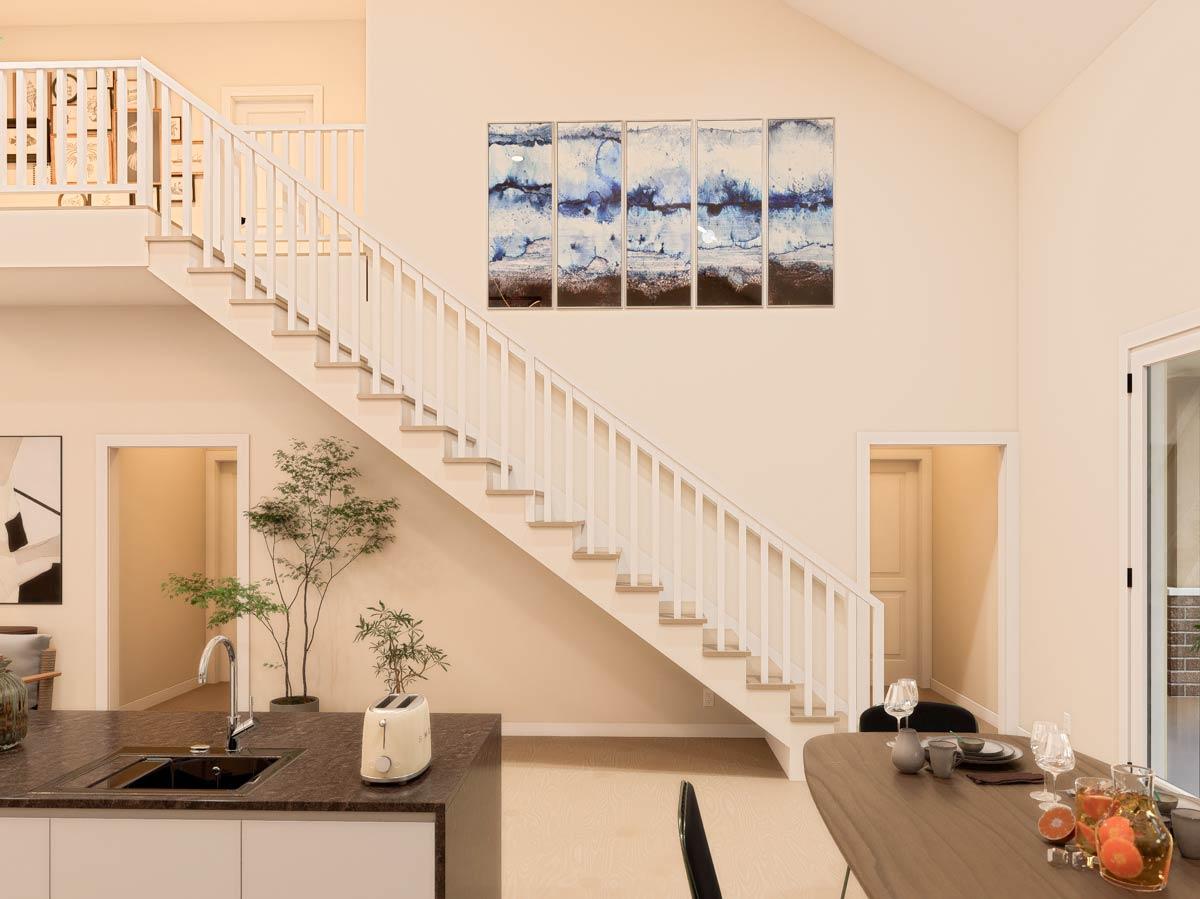 Interior view of a home with a two-story staircase, kitchen island, and dining area.