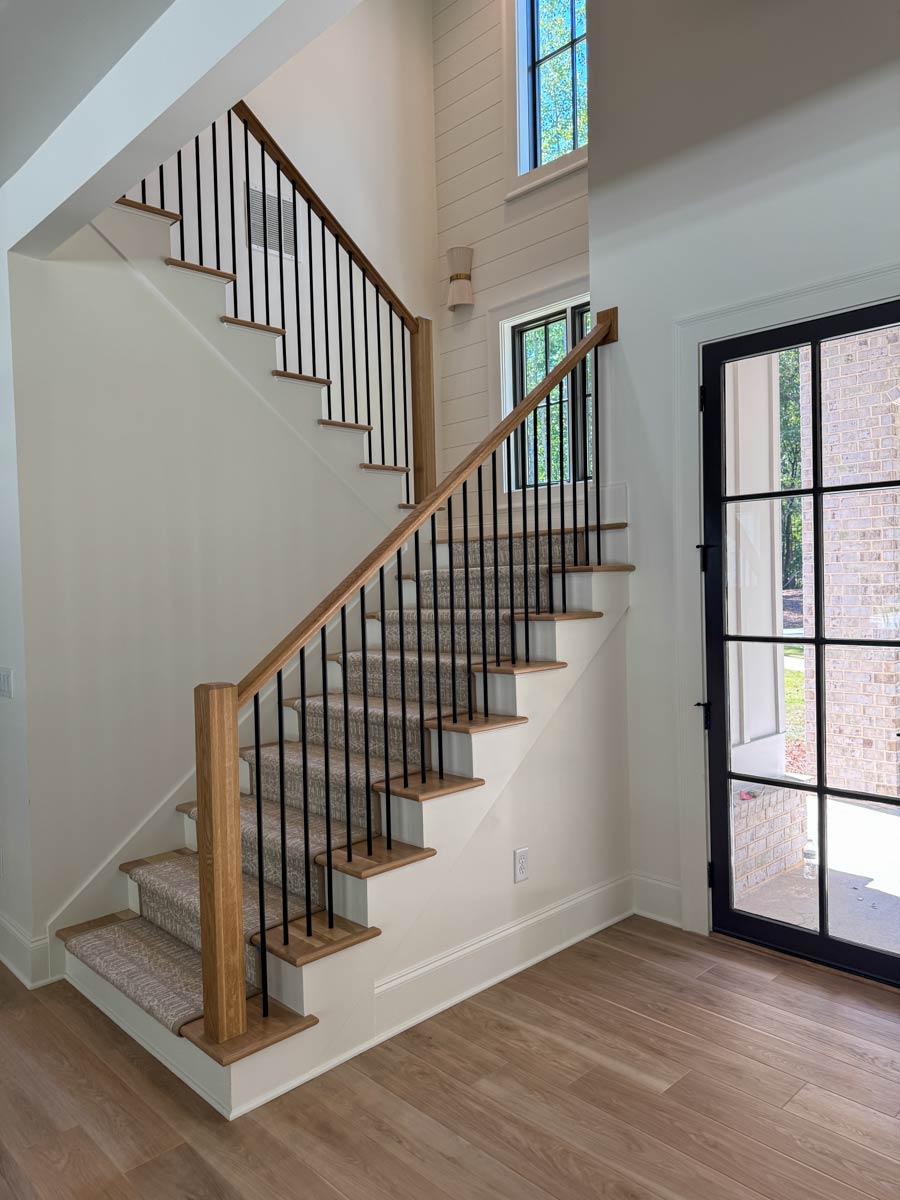 Interior view of staircase with wood treads, black balusters, and shiplap accent wall.