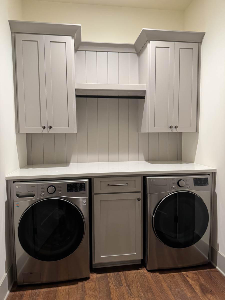 Laundry room with gray cabinets, white countertop, LG washer and dryer, and paneled wall.