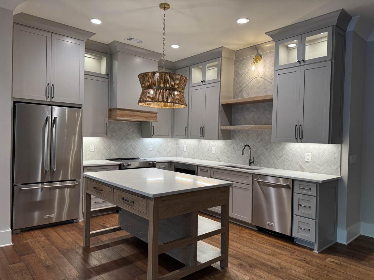 Kitchen with gray cabinets, stainless steel appliances, center island with butcher block, and herringbone backsplash.