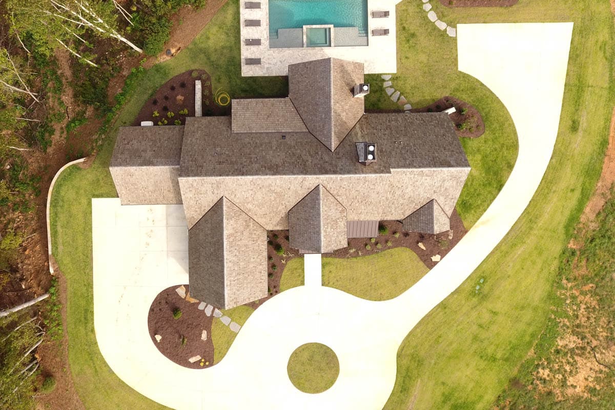 House plan exterior showing a complex roofline with multiple gables and dormers, a circular driveway, and a pool.