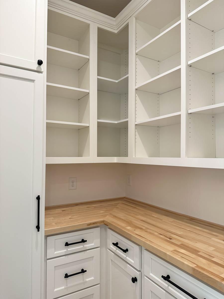 Pantry with white cabinets, butcher block countertops, and built-in shelving.