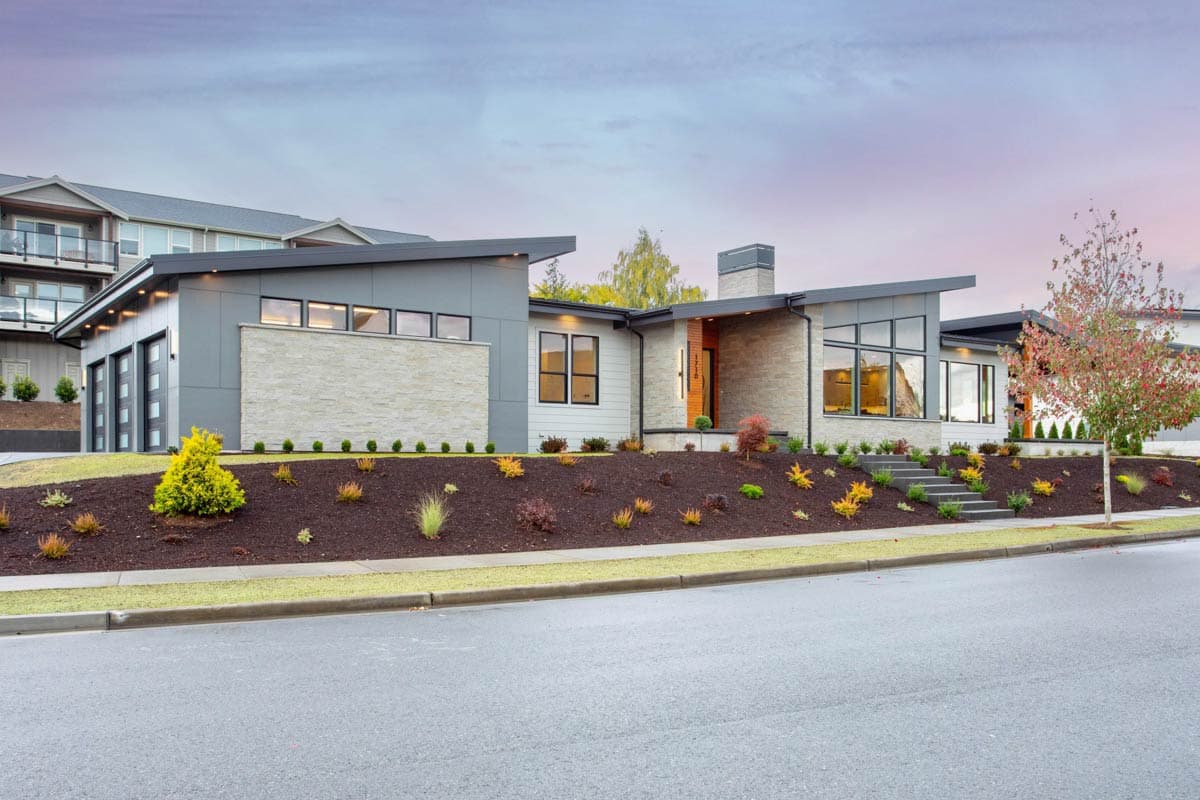 Modern house plan exterior with stone accents, asymmetrical rooflines, large windows, and a three-car garage.