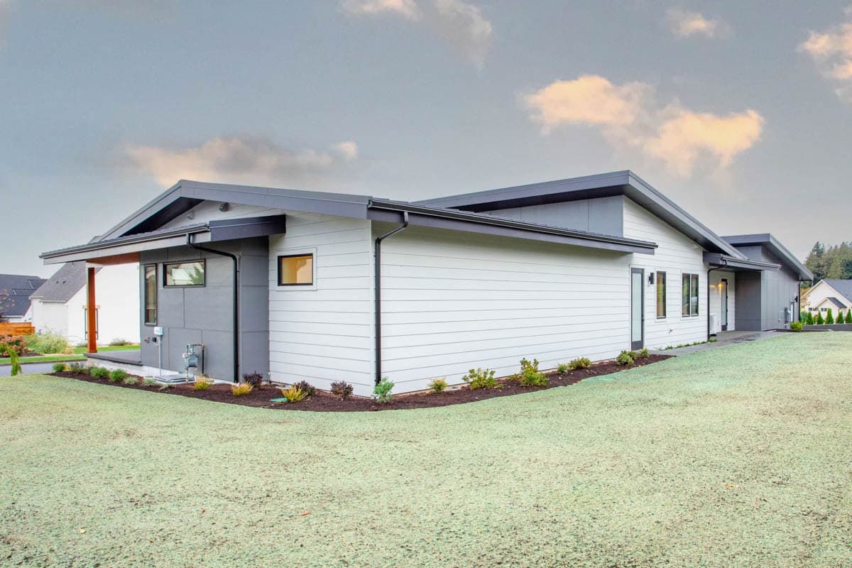 Modern one-story house plan exterior with horizontal siding, mixed materials, and asymmetric gabled rooflines.