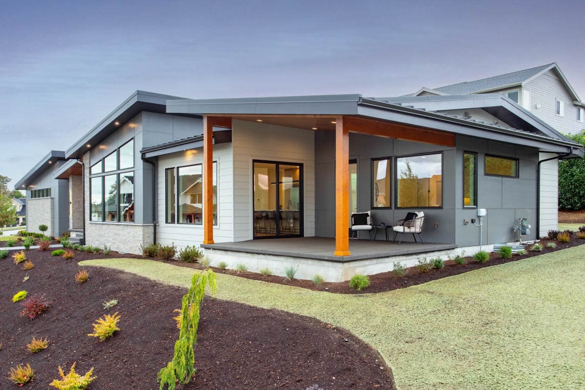 Modern house plan exterior with cantilevered roof, stone base, large windows, and covered porch with wooden posts.
