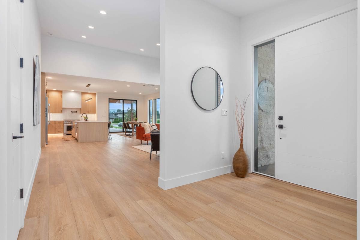 Interior view of a modern home entry with open layout revealing a kitchen with island and dining area beyond.
