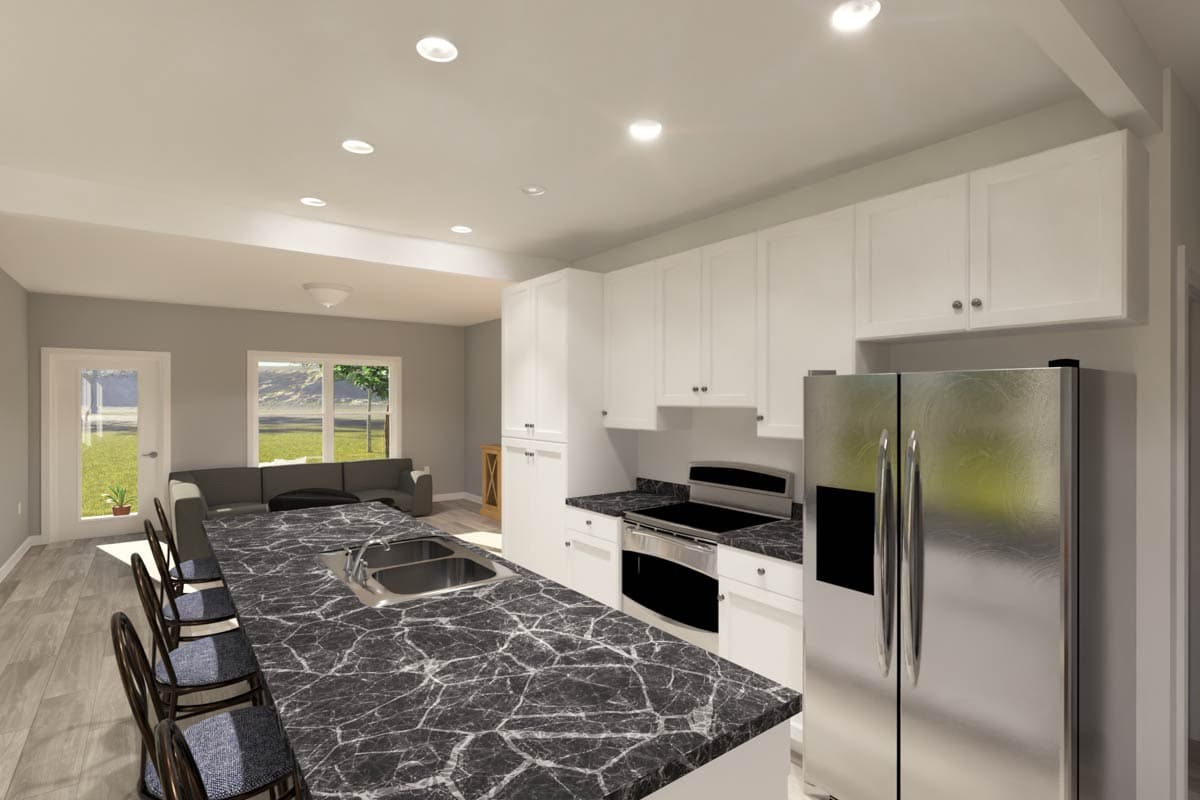 Kitchen with large island, stainless steel appliances, and open access to a living area with sofa and windows.