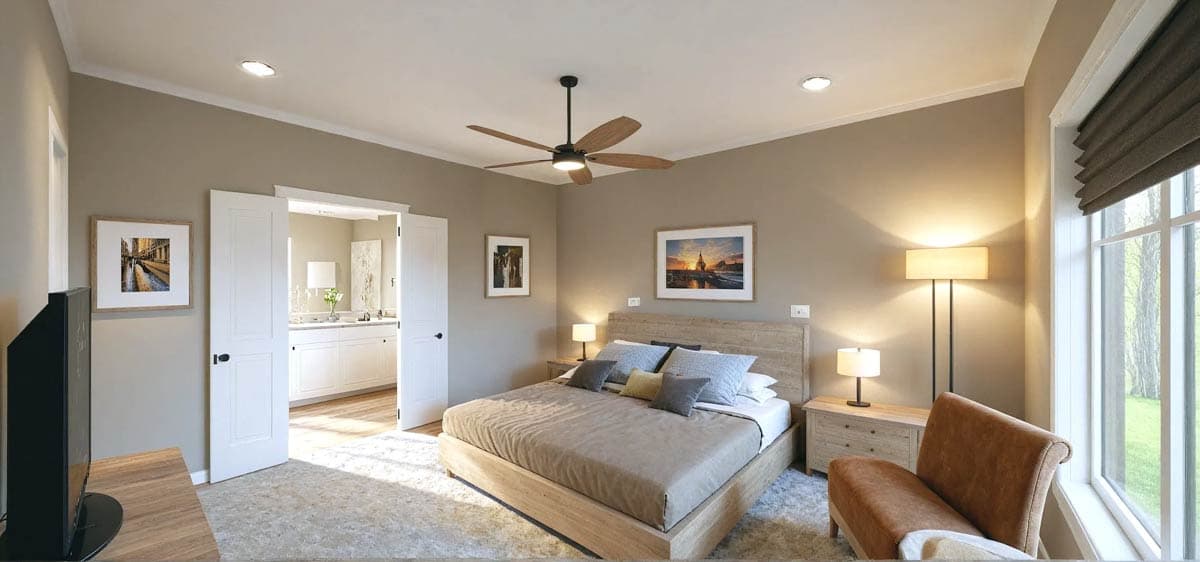 A modern bedroom with a large bed, artwork, and a ceiling fan. Soft lighting illuminates the room with an open doorway to the en suite.