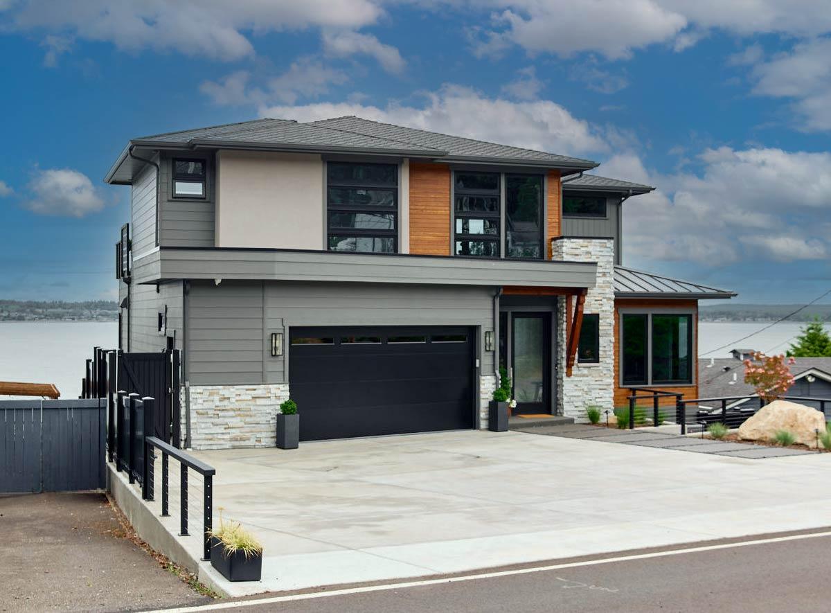 Two-story modern house plan exterior with stone and wood accents, a prominent garage, and multi-pane windows.