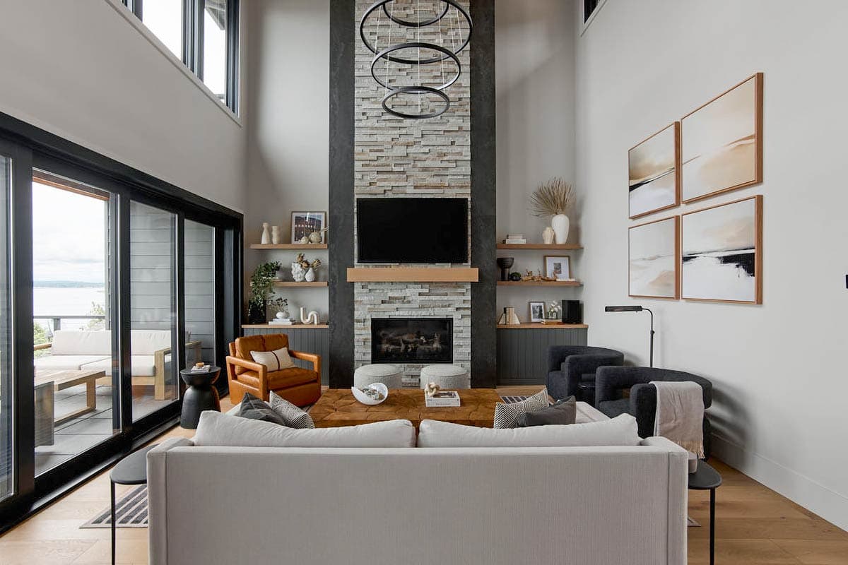 Great room with stacked stone fireplace, large sliding glass doors to deck, and vaulted ceiling.