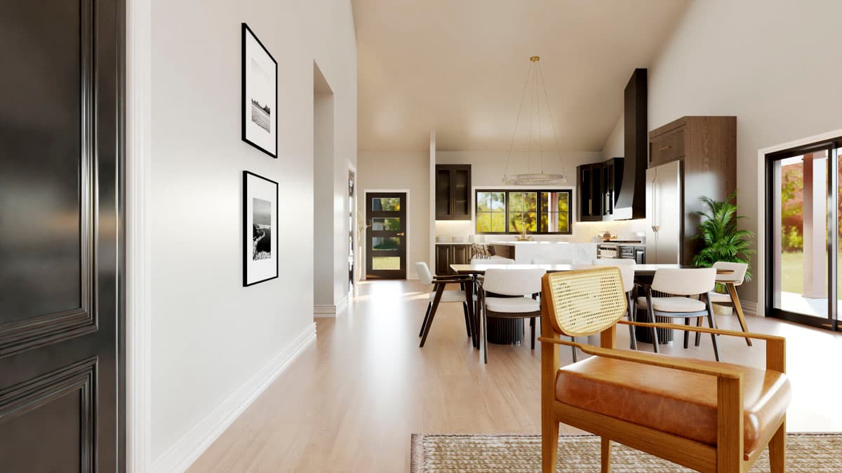 Open-concept dining and kitchen area with a large island, modern cabinetry, and vaulted ceiling. Sliders open to an outdoor patio.