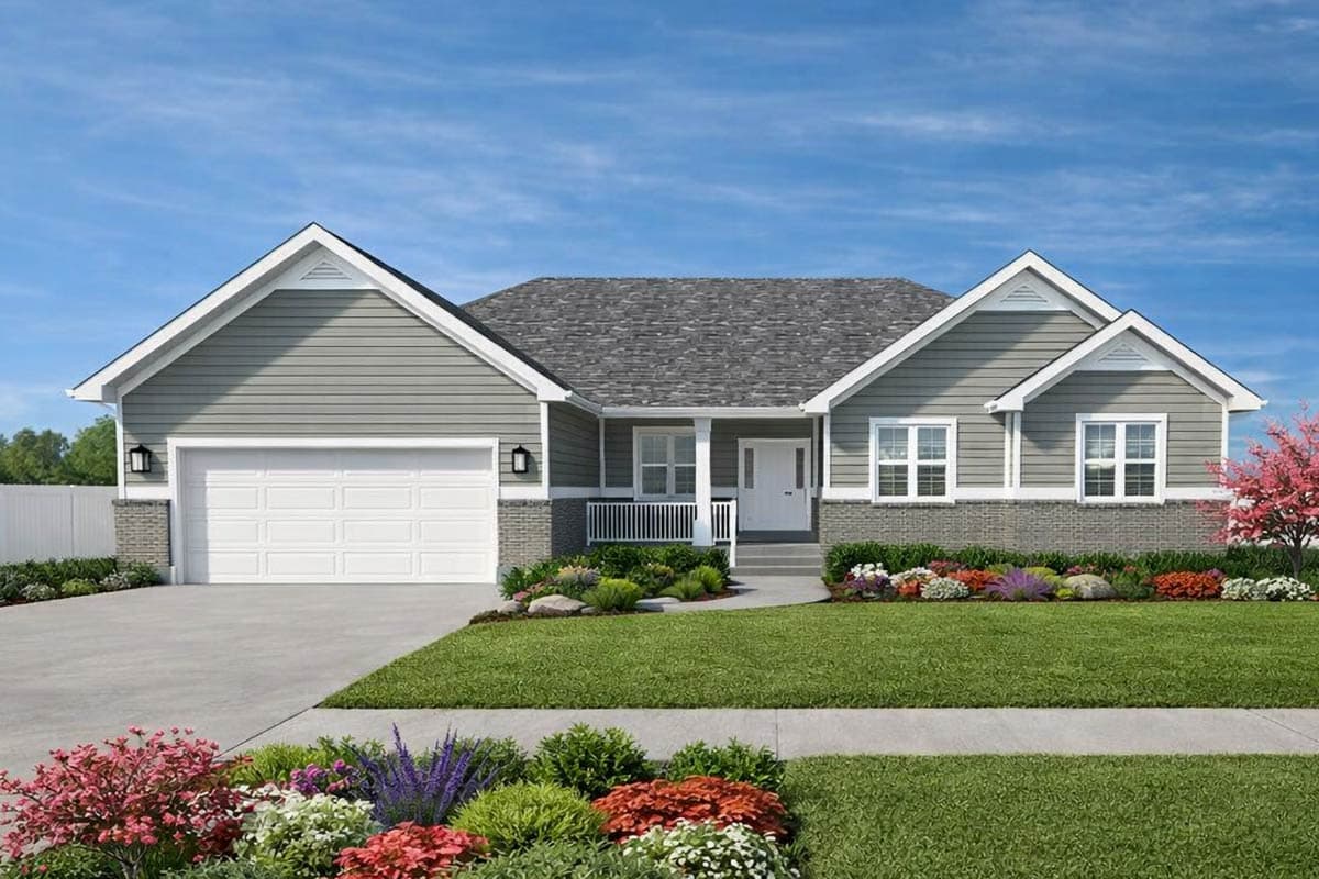 A gray, single-story house with a white garage door, porch, and a well-manicured lawn. Colorful flowers line the walkway leading up to the entrance.