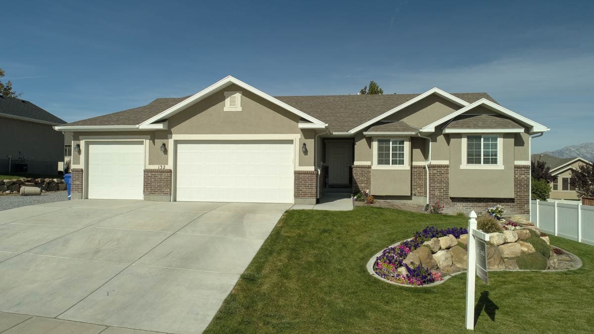 House plan exterior: single-story home with a three-car garage, gable roof, and brick accents.