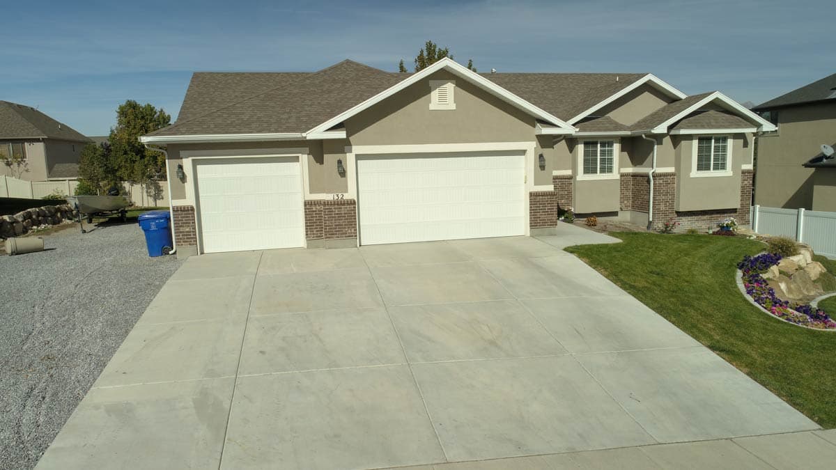 House plan exterior: Ranch style, three-car garage with white doors, prominent gables, and brick accents.