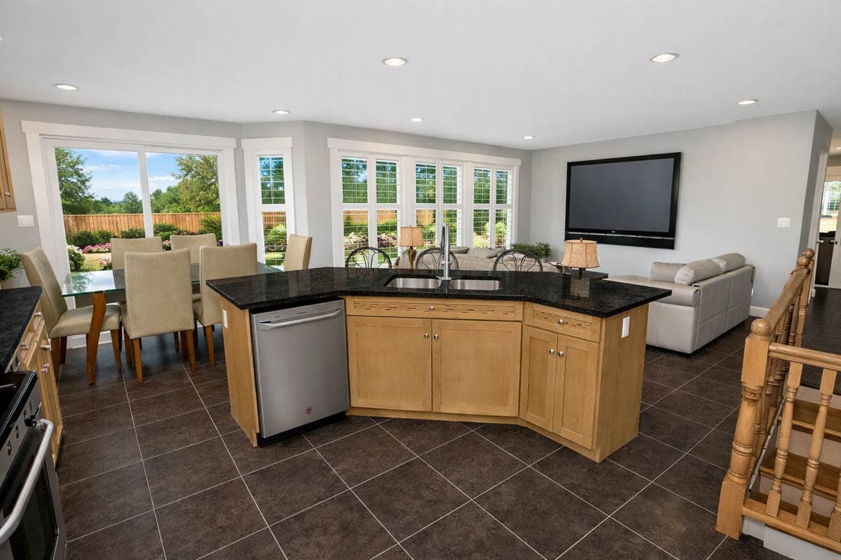 Open-concept kitchen with island, dining area, and living space. Features granite countertops, stainless steel dishwasher, and large windows.