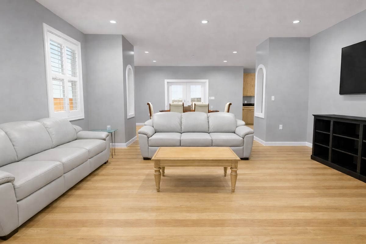 Open-concept living and dining area with light wood floors, gray walls, two sofas, a coffee table, and dining furniture.