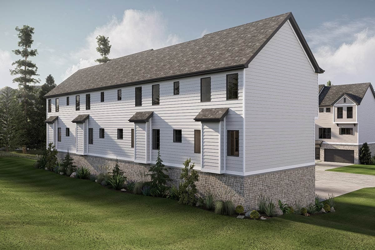Two-story townhouse exterior with horizontal siding, stone foundation, and projecting window bays with gable roofs.