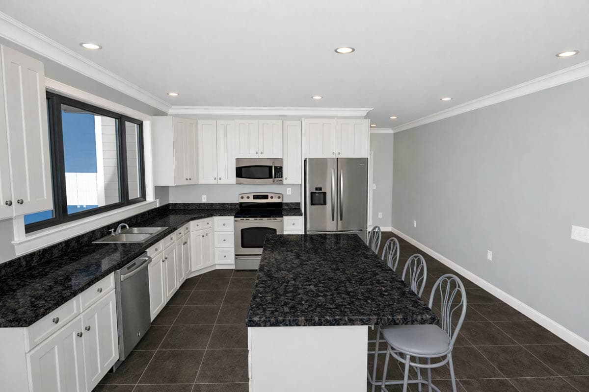 Kitchen with white cabinetry, granite countertops, stainless steel appliances, and a large island with seating.